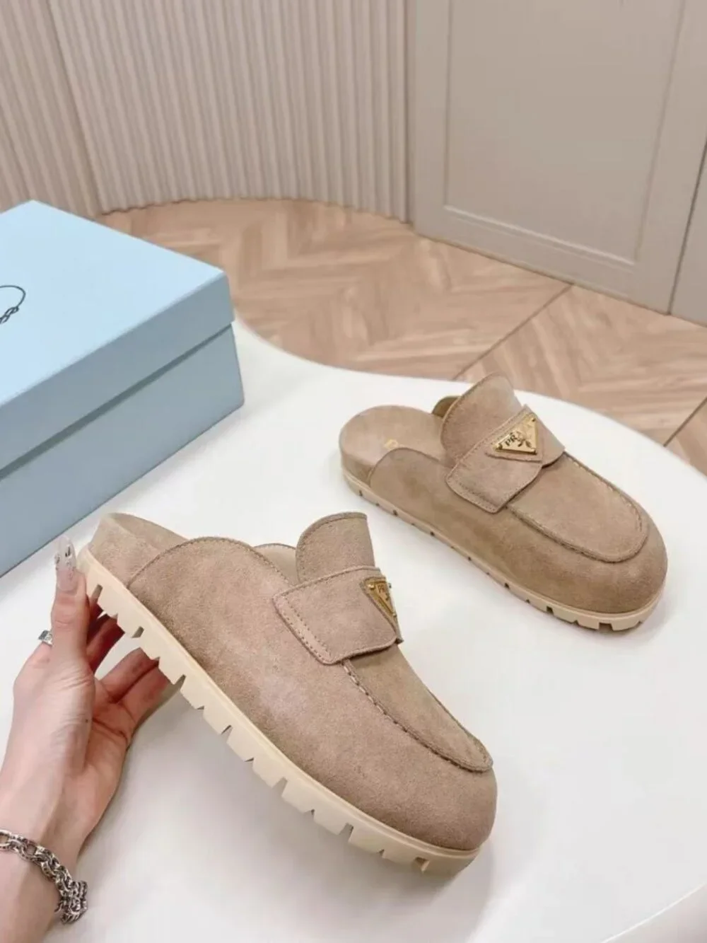 Prada beige slip‑on mules with triangular logo badge